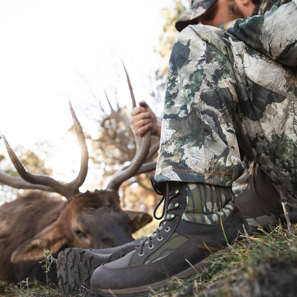 Man sitting with elk after a successful hunt