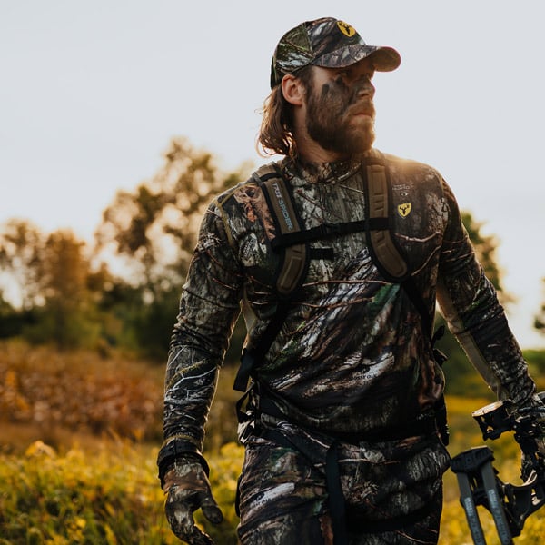 Man walking through field wearing blocker outdoors gear for whitetail doe hunt