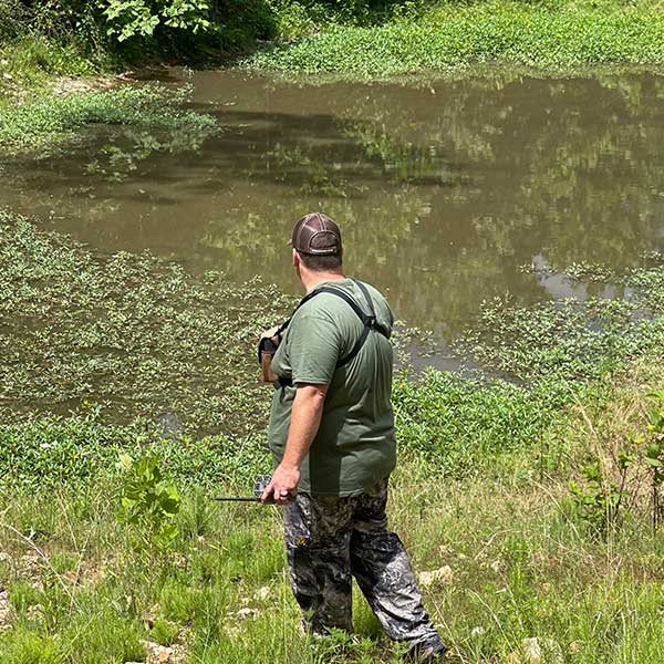 Man Standing by Muddy Water Pond in Summer